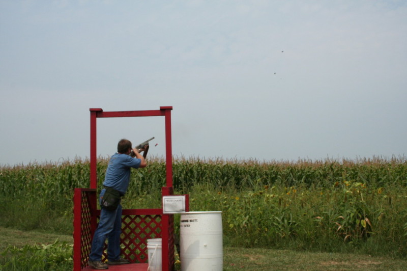 man standing in a stand clay shooting